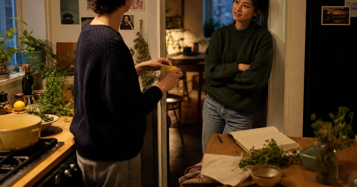 Two people in an apartment kitchen sharing an everyday story