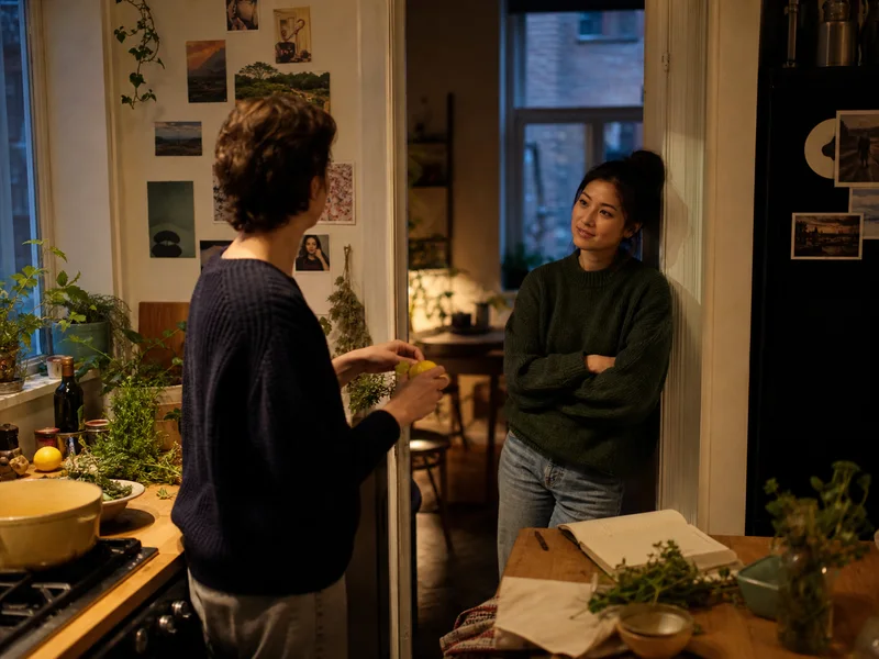 Two people in an apartment kitchen sharing an everyday story